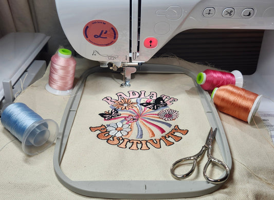 Close-up of vibrant spools of embroidery thread and an embroidery machine working on a custom fabric piece in a well-lit workshop