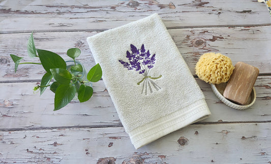 Custom embroidered hand towel folded neatly with natural soap and bathroom decor by Luniquedesigns