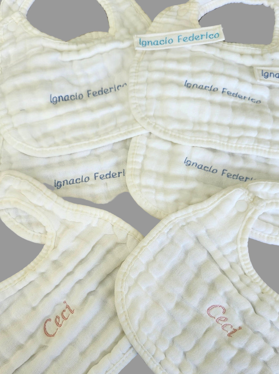 Set of baby bibs with embroidered names on a wooden surface