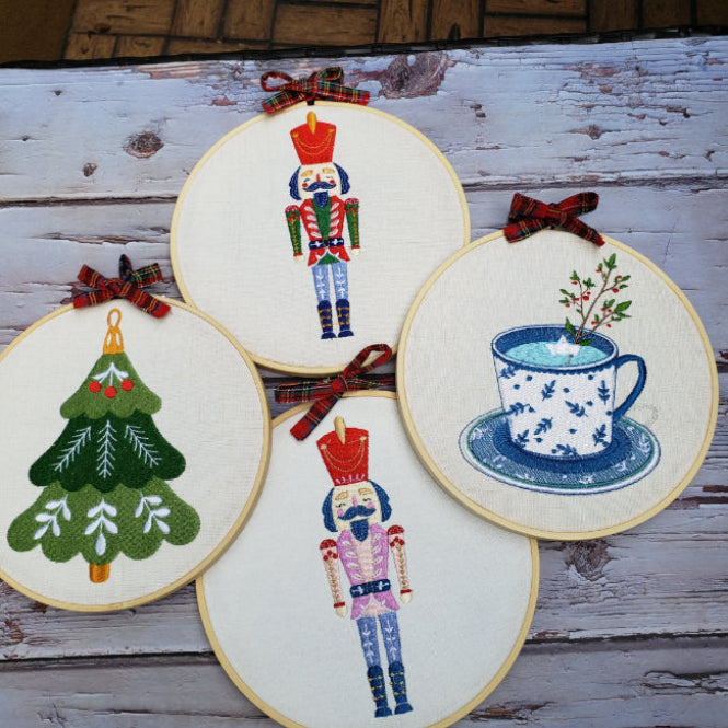 Four embroidered hoops with various designs on a wooden surface