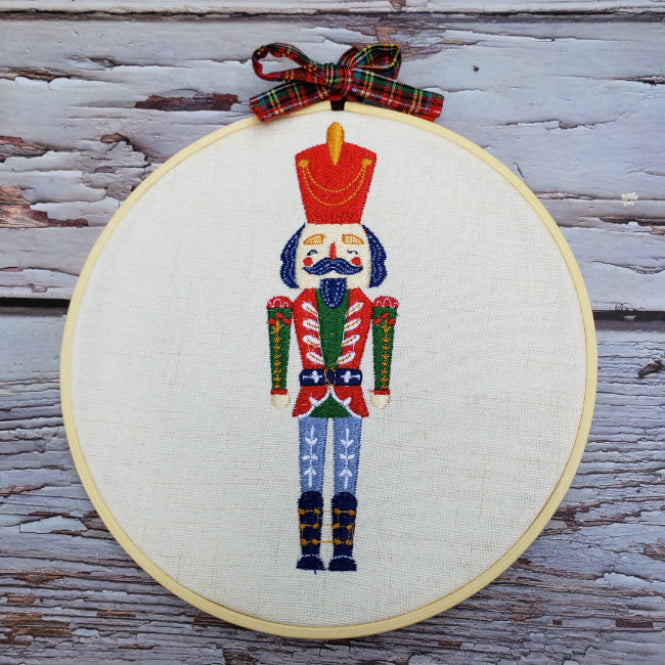 Embroidery of a nutcracker in a hoop on a wooden surface
