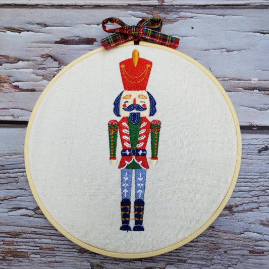 Embroidery of a nutcracker in a hoop on a wooden surface
