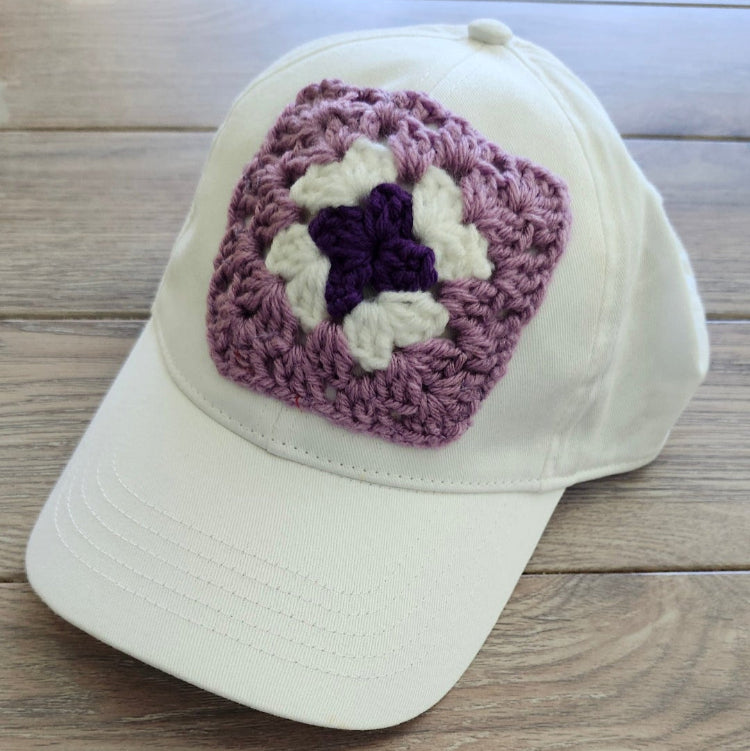 White cap with a purple and white star design on a wooden surface