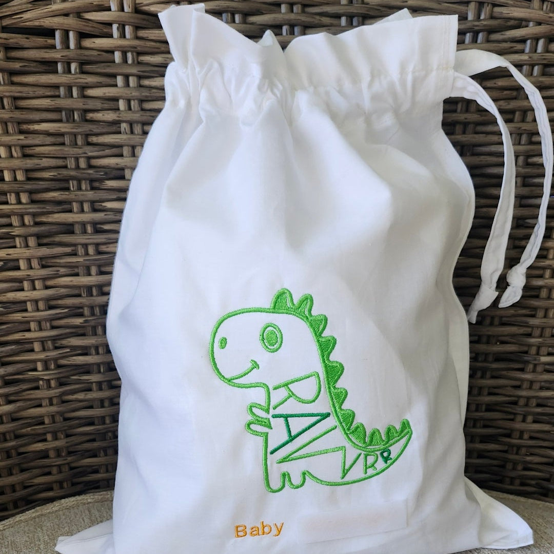 White drawstring bag with green Dinosaur on a textured surface