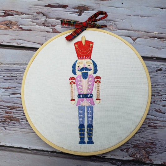 Embroidery hoop with colorful embroidered design on a wooden surface